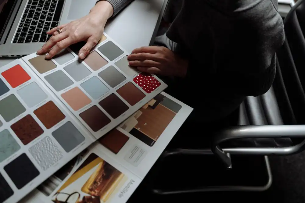 Hands arranging colour swatches beside a laptop