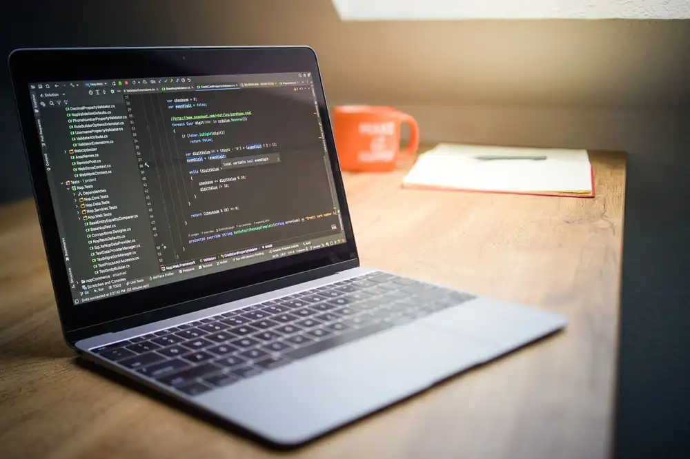 Laptop showing code beside a warm workspace with a mug